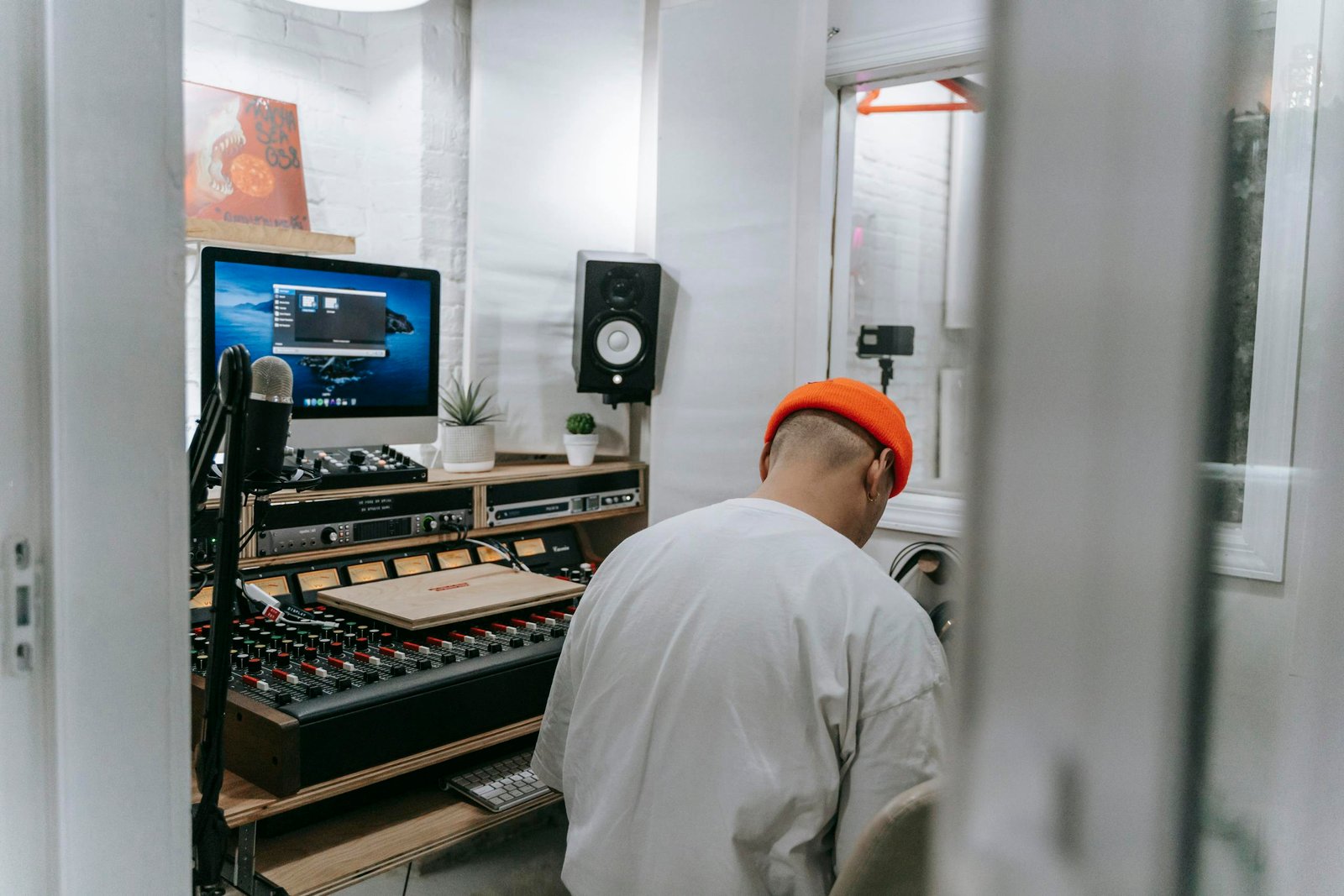 Man in White Shirt Wearing Orange Beanie Sitting Inside Music Studio